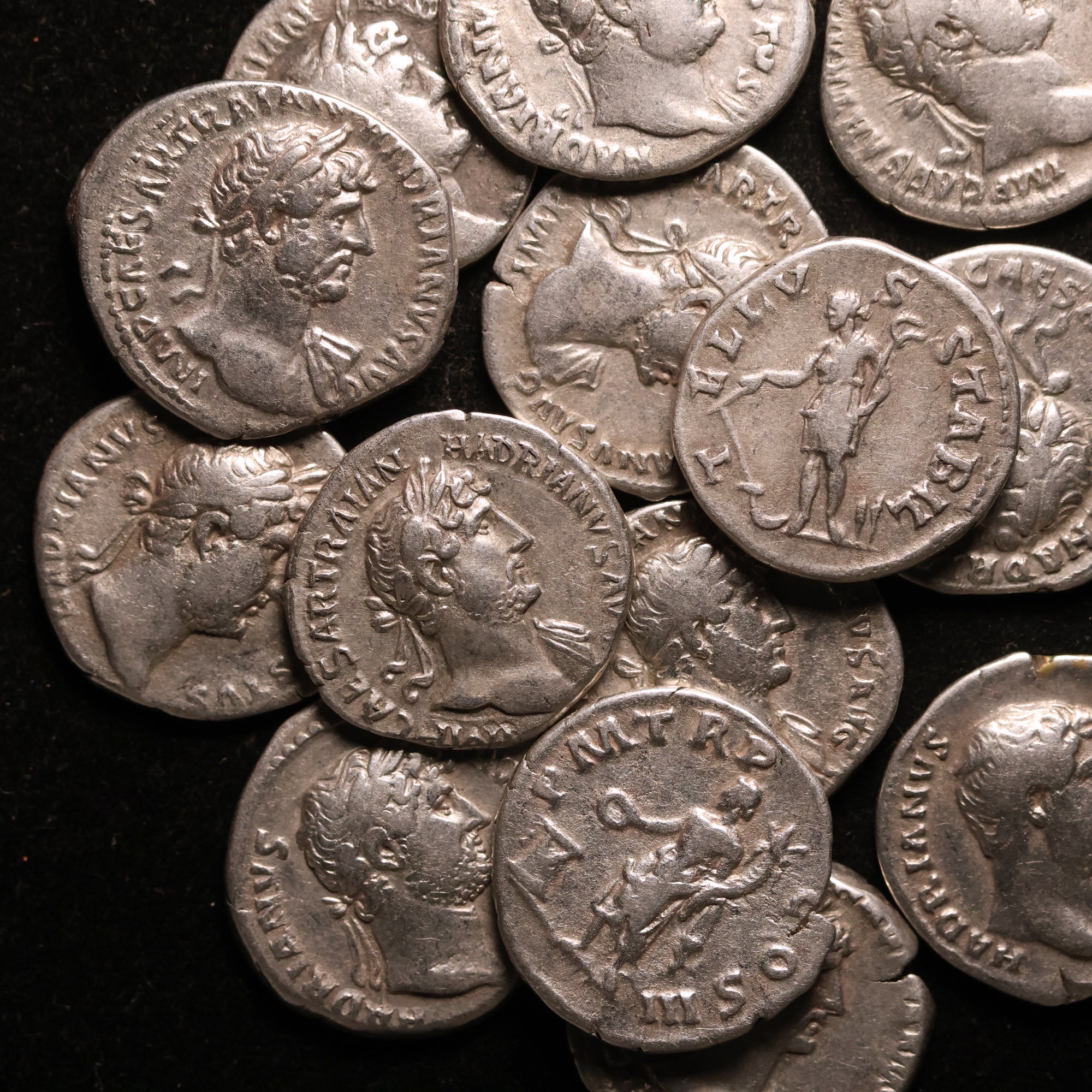 Collection of ancient Roman silver coins with various portraits and inscriptions on a black background.