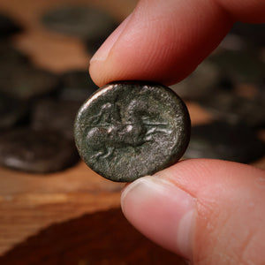 Hand holding a small ancient coin with detailed design