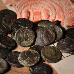 Collection of ancient coins on a textured surface with a decorative background