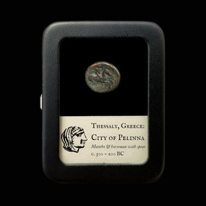 Ancient coin from Thessaly, Greece, displayed in a case with descriptive label.