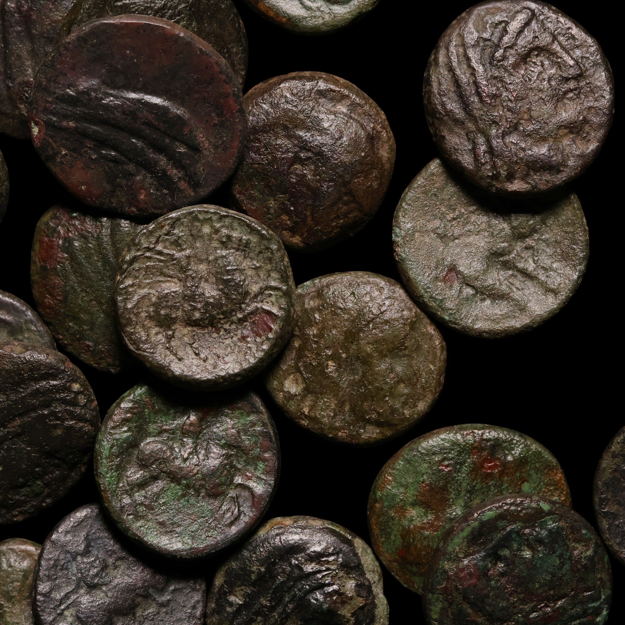 Collection of ancient bronze coins with detailed designs on a dark background